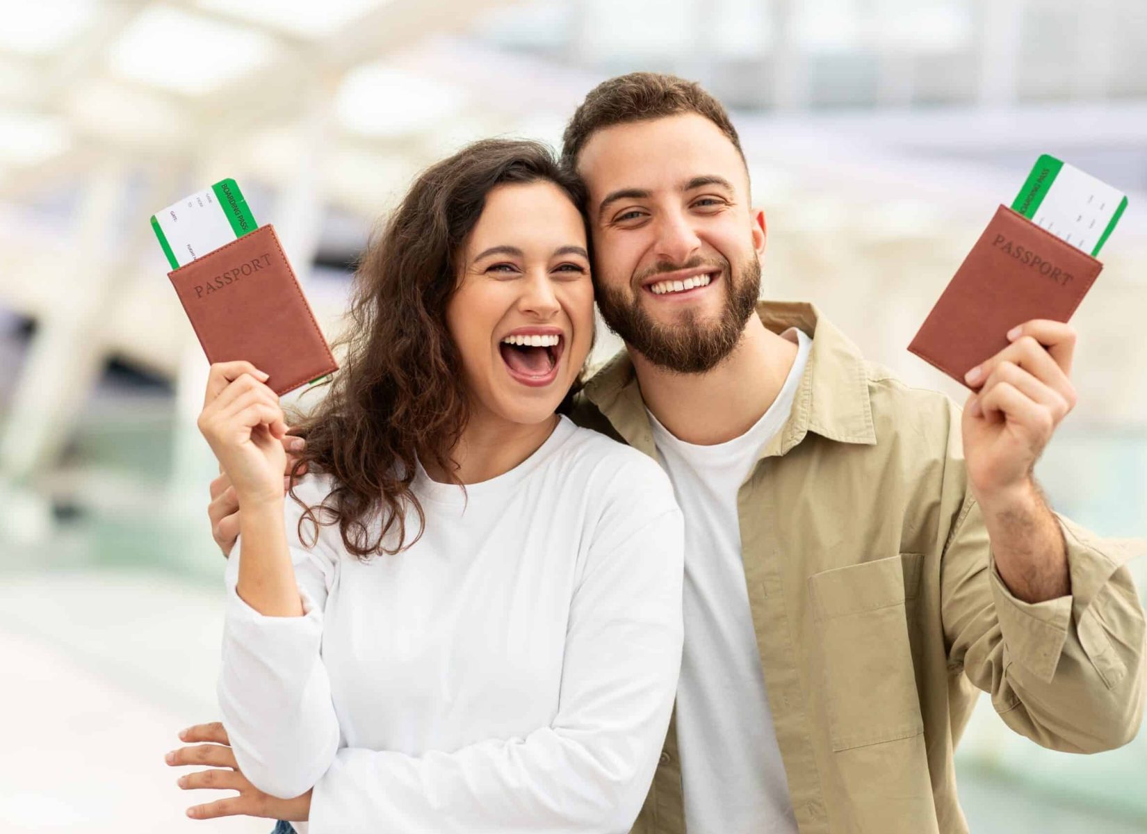 Happy,Young,Man,And,Woman,Holding,Up,Passports,In,Airport